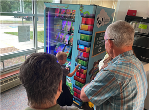 The Volberding family watches a student select a book